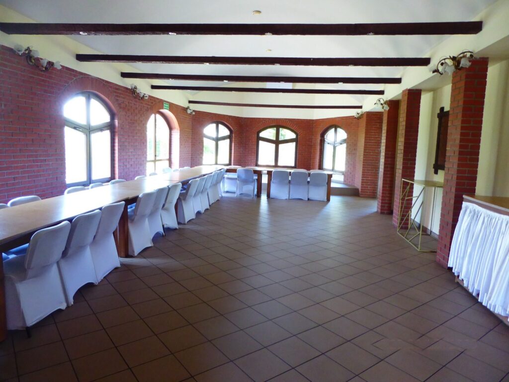 Duża sala Domu Wojciechowego z ceglanymi ścianami, przygotowana do spotkania