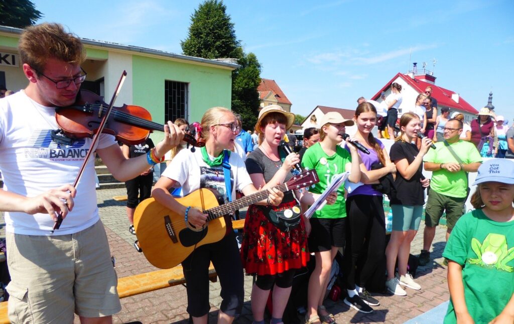 Muzykanci ze skrzypcami i gitarą prowadzą śpiew