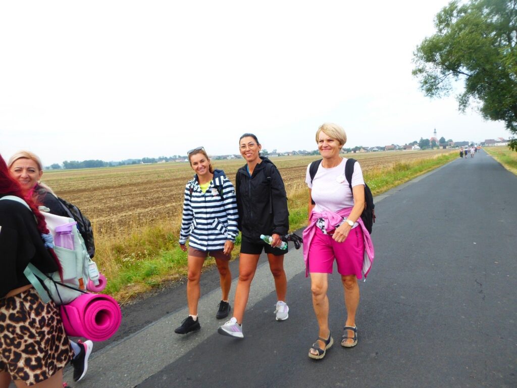 Pielgrzymi na asfaltowej drodze wśród pól